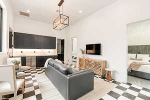 Living room with light flooring, a chandelier, recessed lighting, and a high ceiling