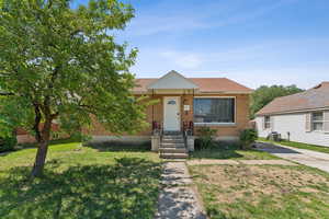 View of front facade with brick siding, a front lawn, and cooling unit
