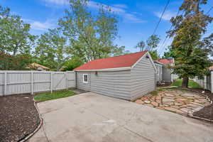 Exterior space with a gate, a patio area, a fenced backyard, and a shingled roof