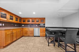 Kitchen featuring appliances with stainless steel finishes, brown cabinets, a sink, backsplash, and recessed lighting