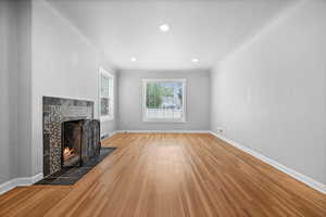 Unfurnished living room featuring a fireplace, wood finished floors, baseboards, and recessed lighting