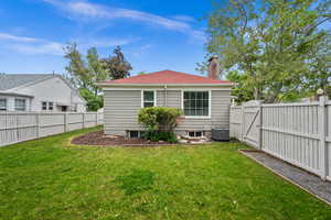 Back of property with a gate, a chimney, and central AC