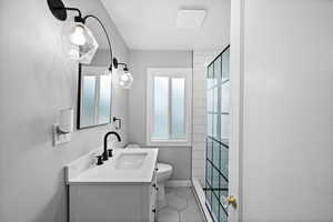Bathroom with toilet, vanity, a shower, tile patterned flooring, and baseboards