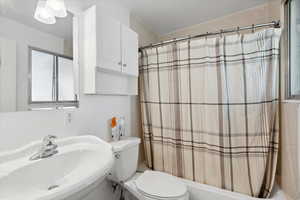 Bathroom featuring a sink, toilet, and shower / bath combo with shower curtain
