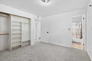Unfurnished bedroom with carpet floors, a closet, ensuite bath, and baseboards