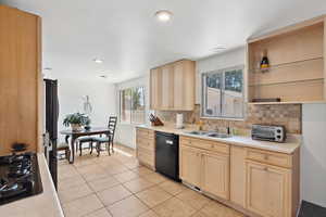 Kitchen featuring black appliances, a sink, light brown cabinetry, decorative backsplash, and recessed lighting