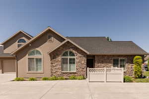 View of front of home with stone siding, stucco siding, driveway, a garage, and roof with shingles