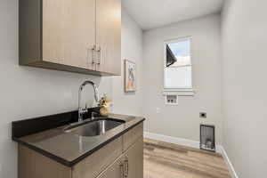 Laundry area featuring cabinet space, light wood-type flooring, hookup for an electric dryer, and hookup for a washing machine