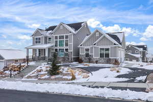 Craftsman-style house with board and batten siding, covered porch, stone siding, and stairway