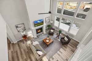 Living area featuring ceiling fan, a glass covered fireplace, a high ceiling, and wood finished floors