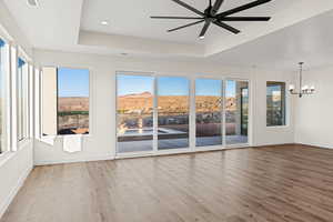 Empty room featuring a tray ceiling, wood finished floors, baseboards, plenty of natural light, and recessed lighting