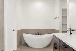 Bathroom featuring vanity, a freestanding bath, wainscoting, tile walls, and tile patterned floors