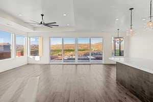 Unfurnished living room featuring a ceiling fan, wood finished floors, a chandelier, recessed lighting, and baseboards