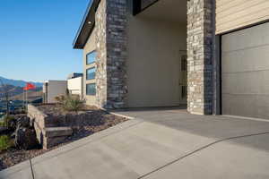 Property entrance with a mountain view, stucco siding, an attached garage, and stone siding