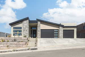Contemporary home featuring a garage, stone siding, and driveway