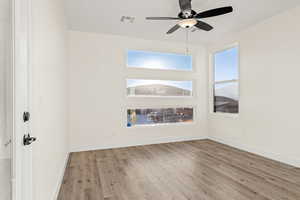 Spare room featuring wood finished floors, ceiling fan, and baseboards