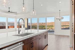 Kitchen featuring a sink, stainless steel dishwasher, light stone counters, recessed lighting, and a chandelier