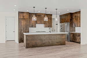 Kitchen featuring appliances with stainless steel finishes, recessed lighting, decorative backsplash, light countertops, and light wood-style floors