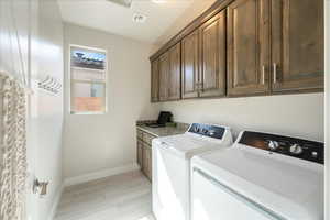 Washroom with independent washer and dryer, cabinet space, baseboards, and wood finish floors