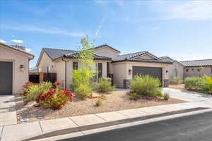 View of front of property featuring stucco siding, a garage, concrete driveway, a tiled roof, and stone siding