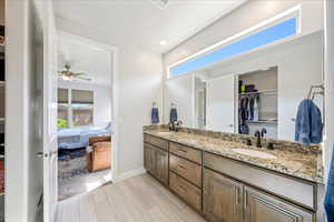 Ensuite bathroom with double vanity, ceiling fan, wood tiled floors, baseboards, and recessed lighting