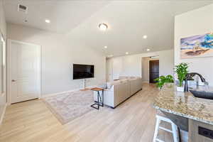 Living room featuring light wood-style flooring, baseboards, recessed lighting, and vaulted ceiling