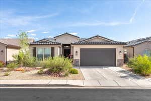 Mediterranean / spanish-style house featuring stone siding, stucco siding, an attached garage, and driveway