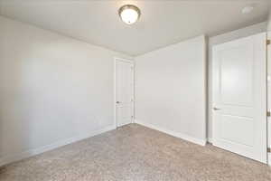 Unfurnished room featuring light carpet, baseboards, and a smoke detector