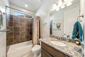 Full bathroom featuring shower / bathtub combination with curtain, vanity, and toilet