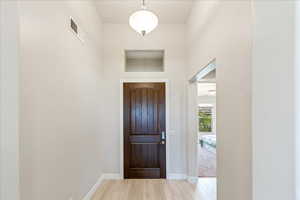Entryway with light wood-style flooring, baseboards, and a towering ceiling