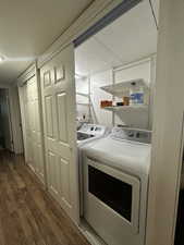 Laundry area with washing machine and clothes dryer and wood finished floors