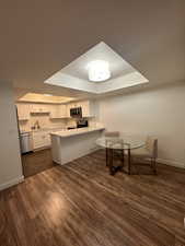 Kitchen with stainless steel appliances, a raised ceiling, baseboards, and a peninsula