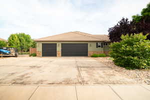 View of front of house with stone siding, concrete driveway, a tile roof, a garage, and stucco siding