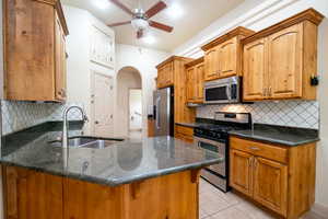 Kitchen featuring stainless steel appliances, a peninsula, a sink, ceiling fan, and arched walkways