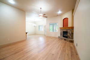Unfurnished living room with a fireplace, a ceiling fan, light wood-type flooring, and baseboards