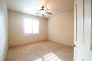 Carpeted spare room featuring ceiling fan and baseboards