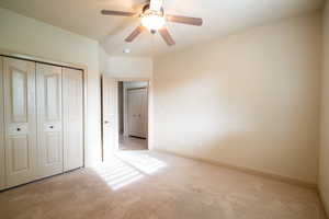 Unfurnished bedroom with carpet floors, a closet, baseboards, and a ceiling fan