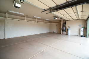 Garage featuring gas water heater, strapped water heater, and a garage door opener