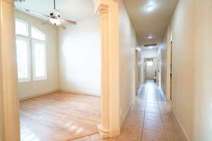 Hall with plenty of natural light, decorative columns, and light tile patterned floors