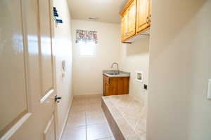 Laundry room with hookup for a washing machine, cabinet space, light tile patterned flooring, and baseboards