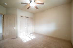 Unfurnished bedroom featuring carpet, a closet, baseboards, and a ceiling fan
