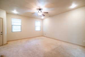 Empty room featuring light carpet, ceiling fan, and baseboards