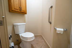 Bathroom featuring toilet, tile patterned floors, and baseboards