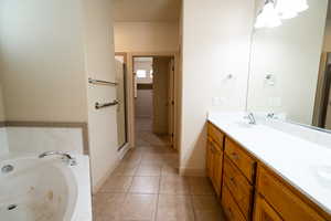 Bathroom with double vanity, a whirlpool tub, a stall shower, tile patterned floors, and baseboards