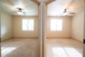 Carpeted empty room featuring a ceiling fan and baseboards