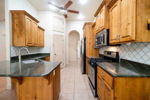 Kitchen with appliances with stainless steel finishes, a sink, a peninsula, a breakfast bar area, and light tile patterned floors