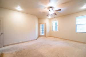 Spare room featuring ceiling fan, light colored carpet, and baseboards