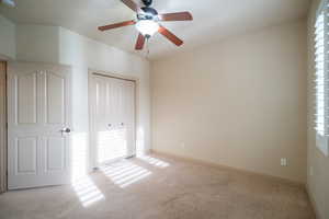 Unfurnished bedroom with carpet, a closet, baseboards, and a ceiling fan