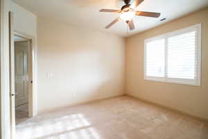 Carpeted spare room featuring ceiling fan and baseboards