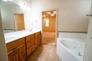 Full bath with a ceiling fan, a jetted tub, double vanity, and tile patterned floors